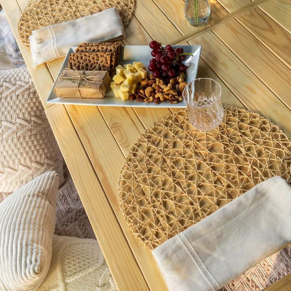 Overhead view of the table: woven mats, linen napkins, cut-glass tumbler and a board of cheese, grapes, nuts and crackers.